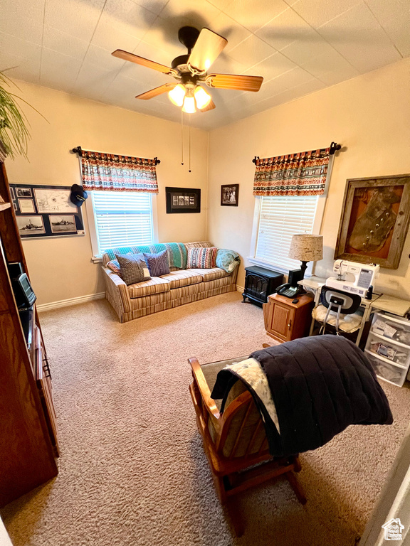 Carpeted living area with a ceiling fan and baseboards