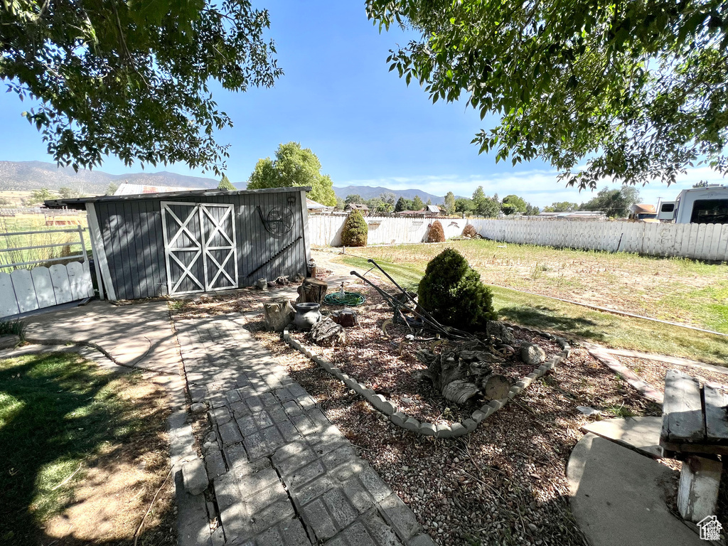 View of yard featuring an outbuilding, a mountain view, and fence