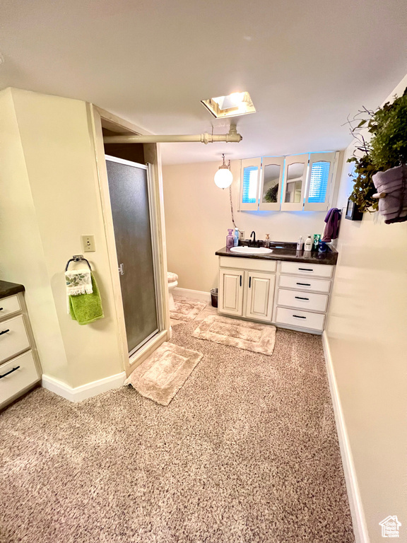 Full bathroom featuring a stall shower, baseboards, toilet, and vanity