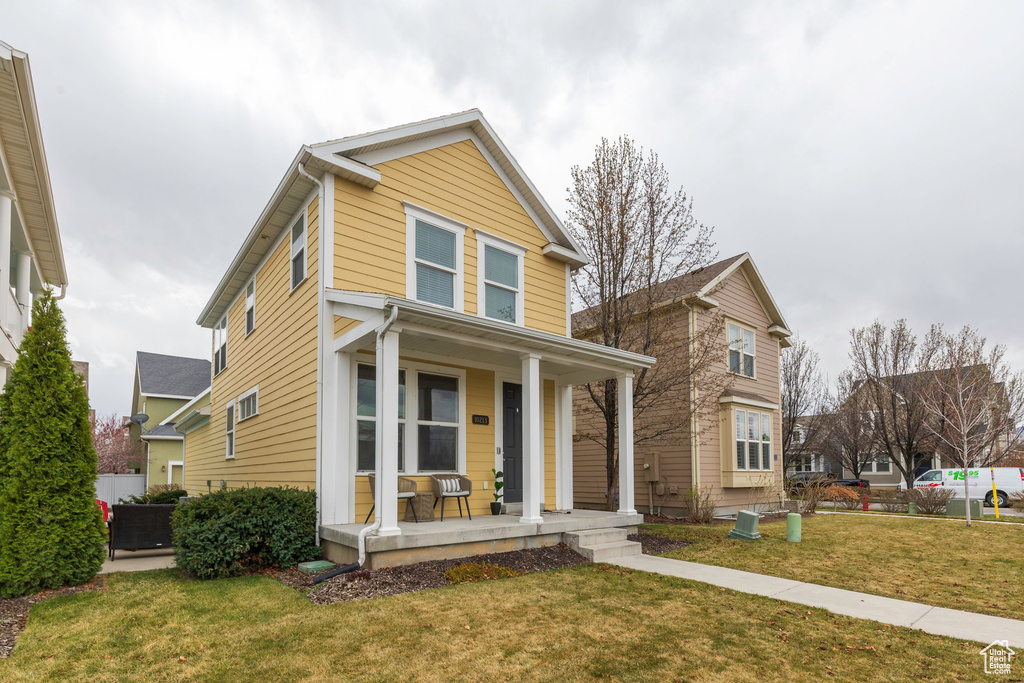 Traditional-style home featuring covered porch and a front yard