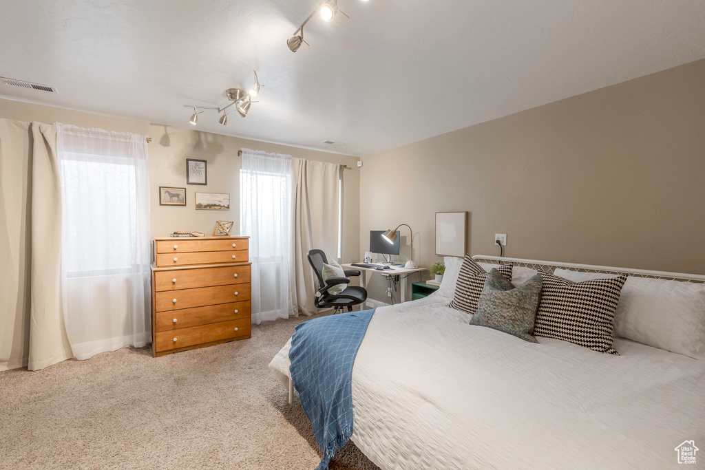 Bedroom featuring rail lighting, visible vents, and light colored carpet
