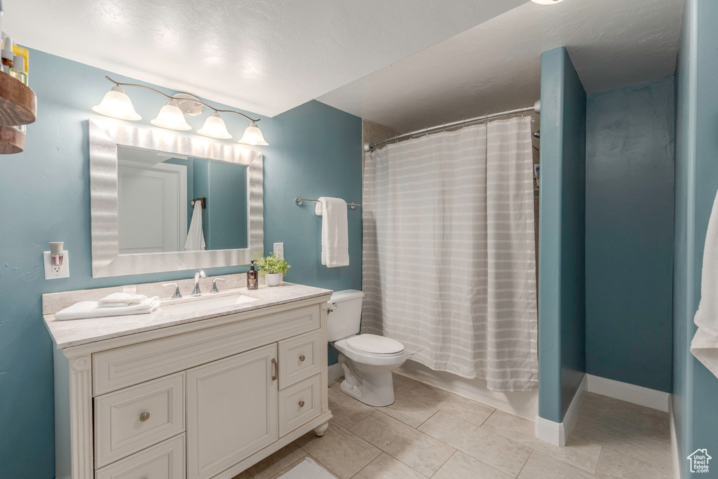 Bathroom with baseboards, toilet, vanity, and tile patterned floors