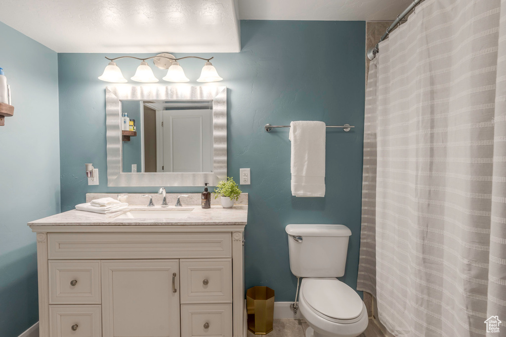 Full bath featuring baseboards, a shower with shower curtain, toilet, and vanity