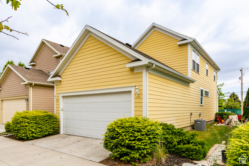 View of property exterior with driveway, central air condition unit, and a garage