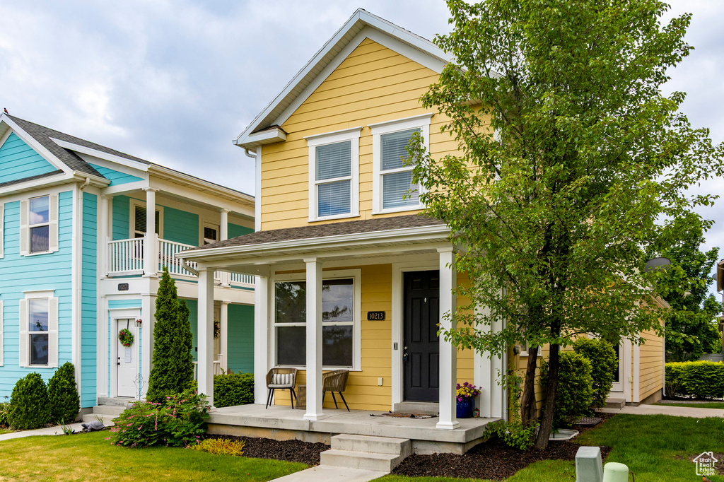 View of front of property featuring covered porch and a front yard