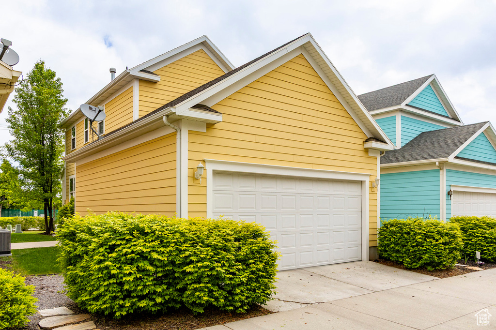 View of home's exterior featuring driveway, central air condition unit, and an attached garage