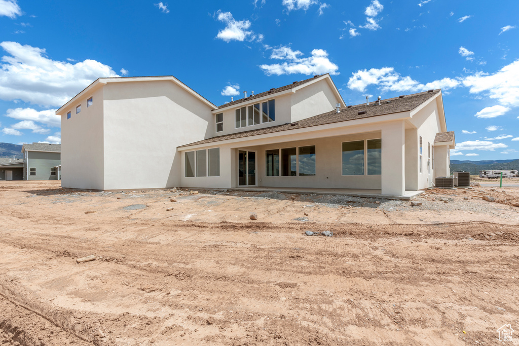 Rear view of house featuring stucco siding and central AC unit