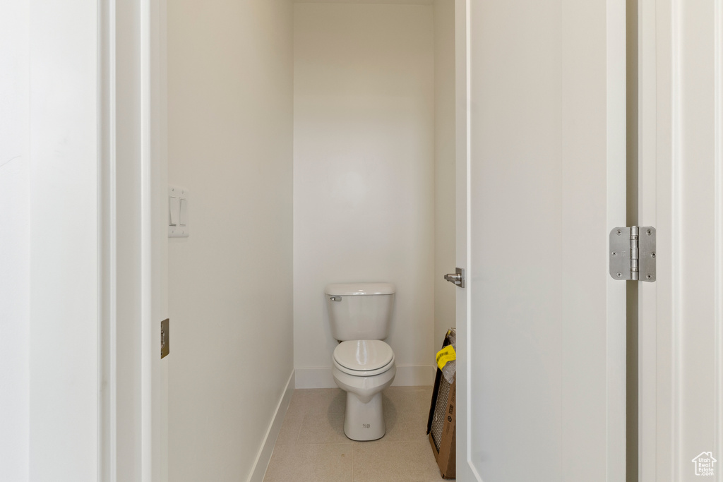 Bathroom with toilet, baseboards, and tile patterned floors