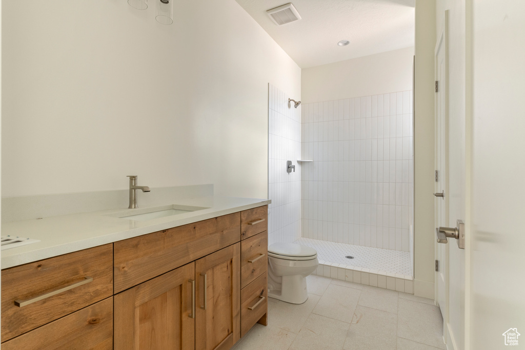 Full bathroom with tiled shower, toilet, and vanity