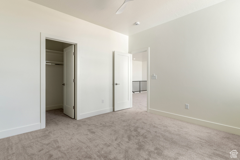 Unfurnished bedroom featuring carpet flooring, a walk in closet, and baseboards