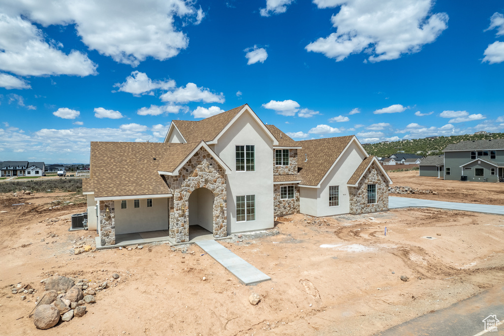View of front of house with stone siding, stucco siding, a shingled roof, and a garage