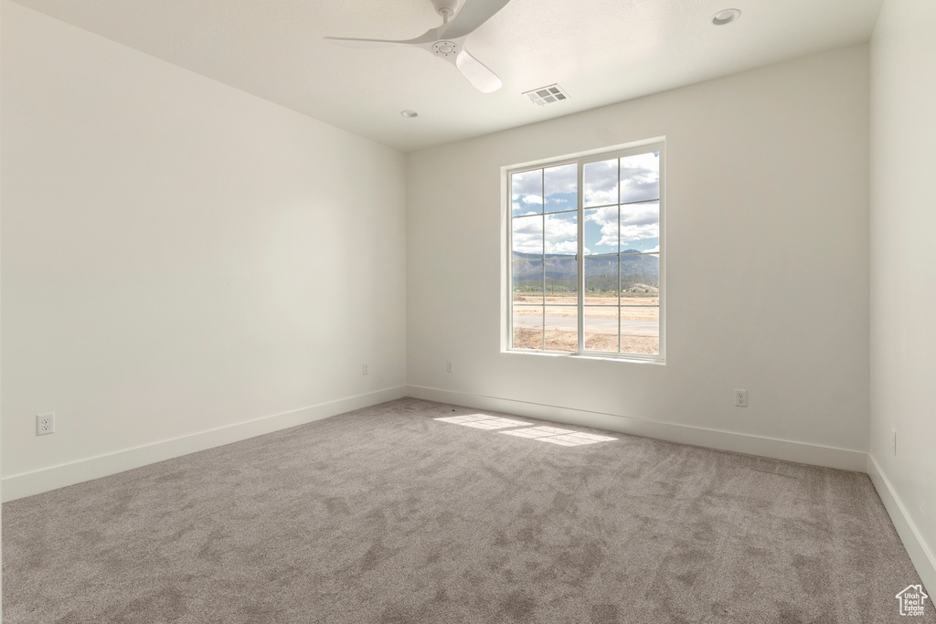 Spare room featuring carpet floors, baseboards, and ceiling fan