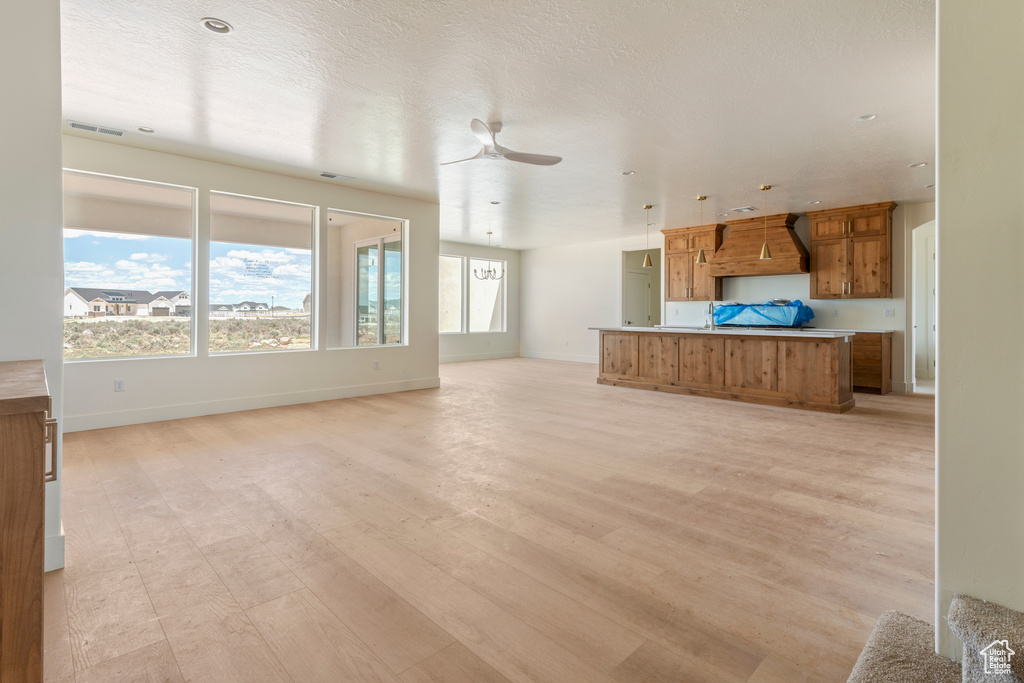 Unfurnished living room with light wood-style flooring, baseboards, and a ceiling fan