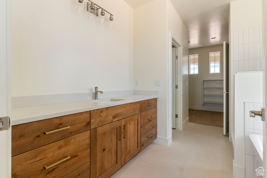 Bathroom featuring vanity, baseboards, and a tub