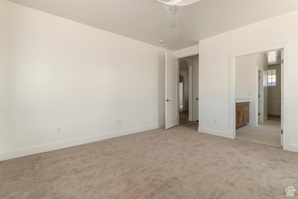 Unfurnished bedroom featuring light colored carpet, arched walkways, and baseboards