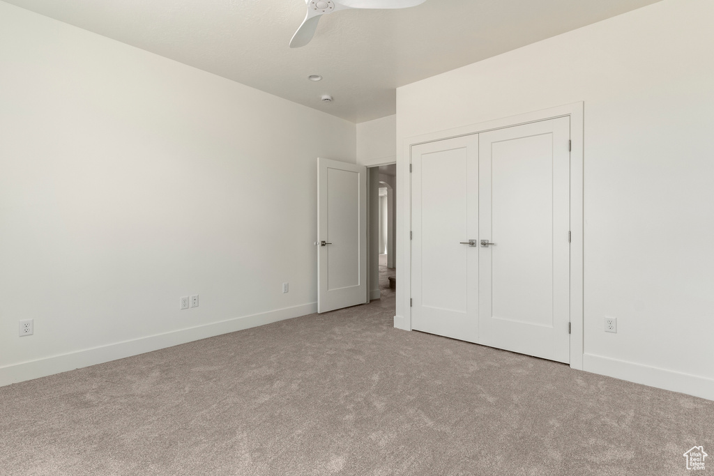 Unfurnished bedroom featuring carpet flooring, baseboards, and a ceiling fan