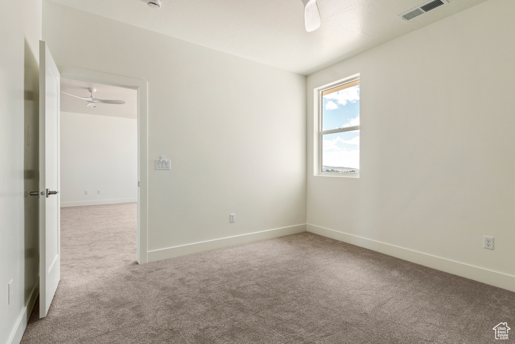 Carpeted empty room featuring a ceiling fan and baseboards