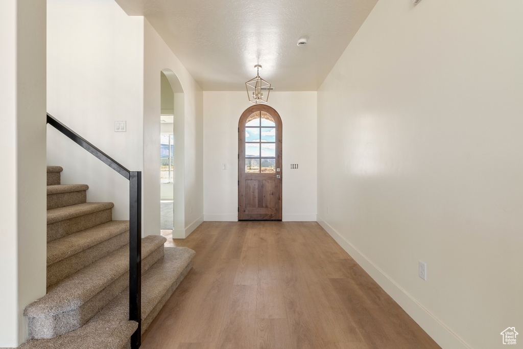 Entrance foyer featuring arched walkways, light wood-type flooring, baseboards, and stairs