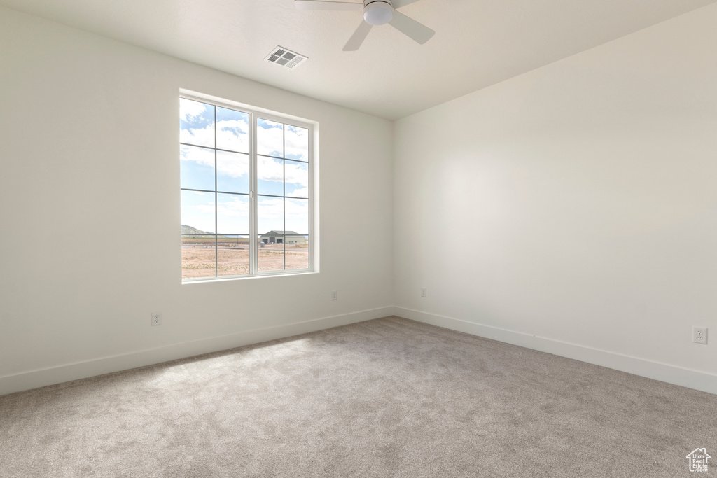 Empty room featuring baseboards, carpet, and ceiling fan