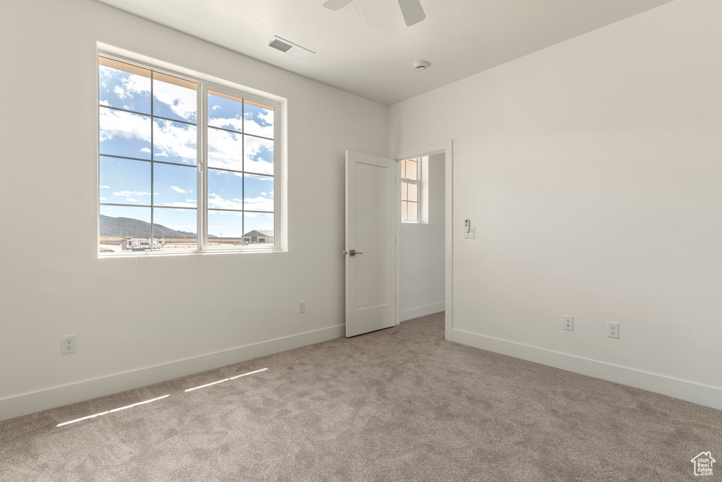 Carpeted empty room featuring baseboards and ceiling fan