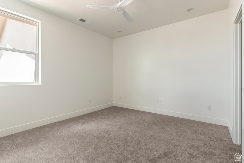 Carpeted empty room featuring a ceiling fan and baseboards