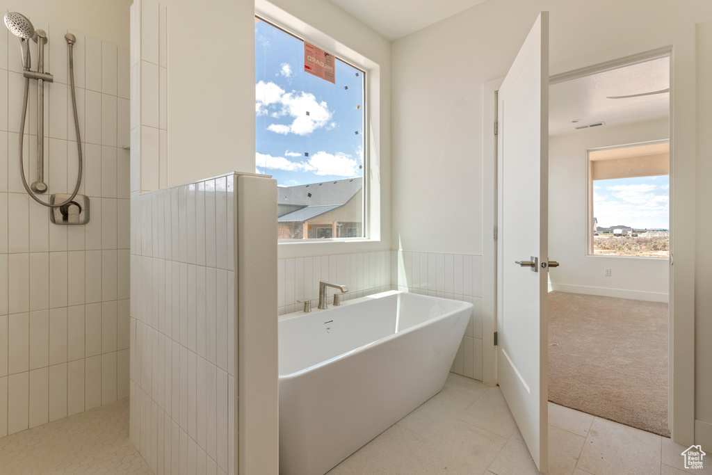 Full bathroom featuring a soaking tub, tiled shower, a wainscoted wall, and tile patterned floors