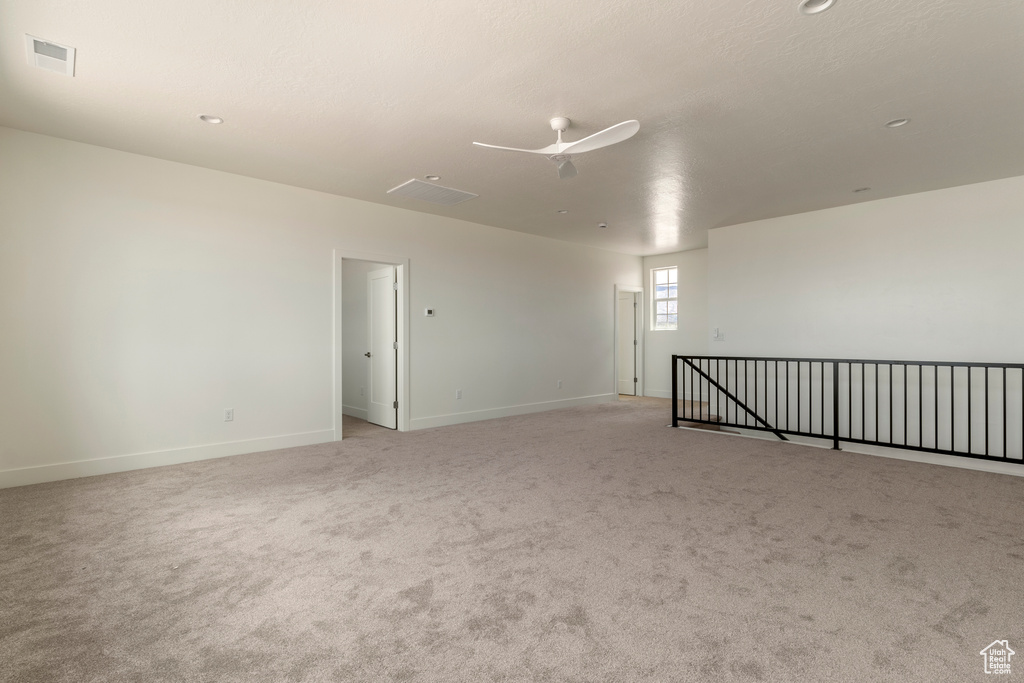 Unfurnished room featuring ceiling fan, light carpet, and baseboards