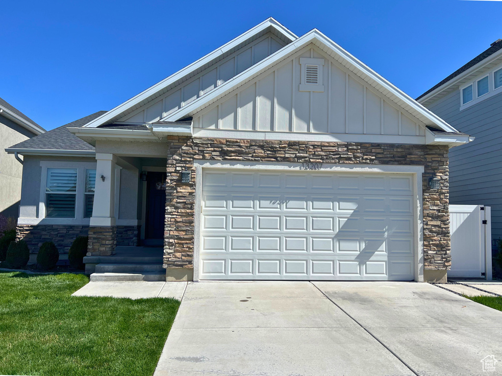Craftsman inspired home featuring board and batten siding, stone siding, driveway, and an attached garage