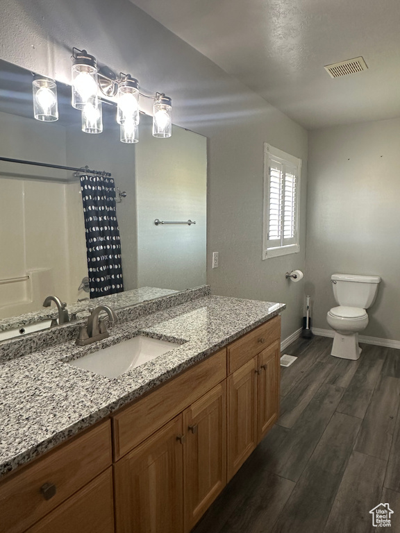 Full bath with visible vents, baseboards, wood finished floors, toilet, and vanity