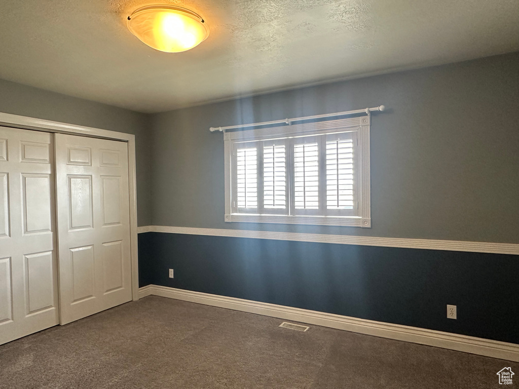 Unfurnished bedroom featuring a closet, baseboards, visible vents, and carpet