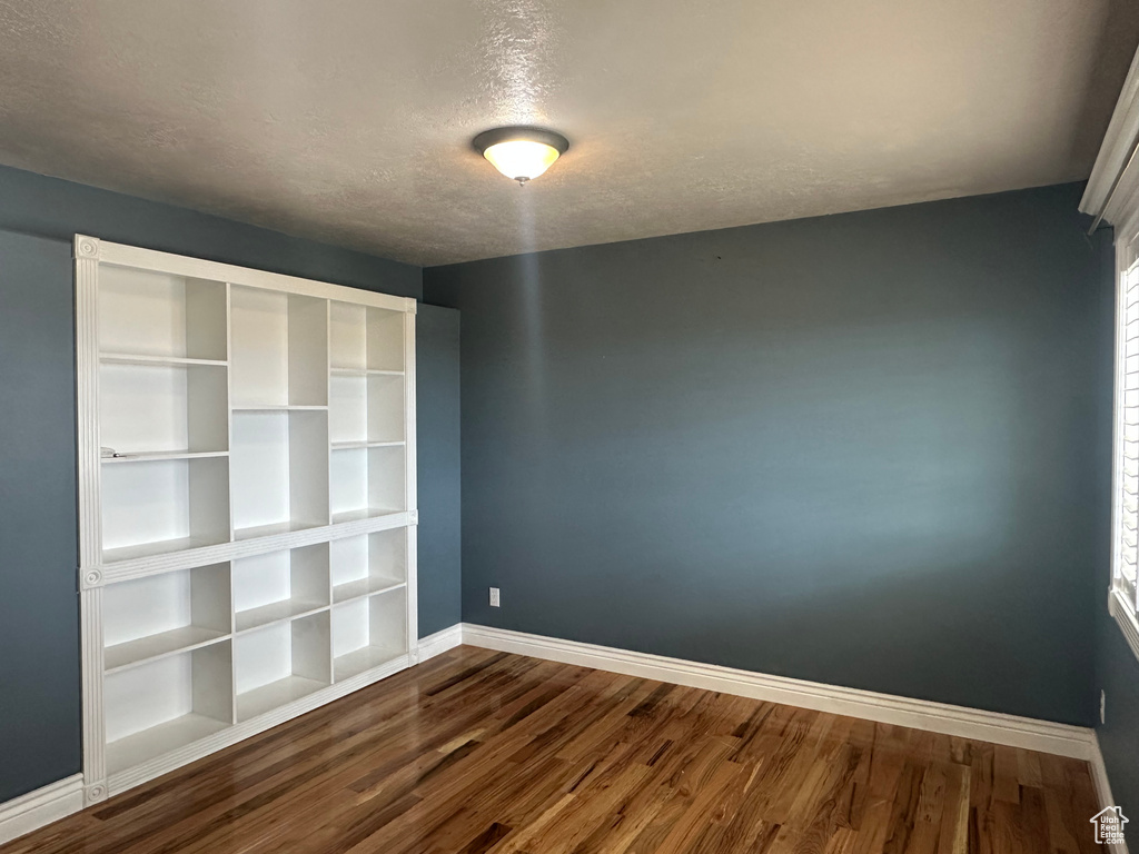Spare room with baseboards, a textured ceiling, and dark wood-style floors
