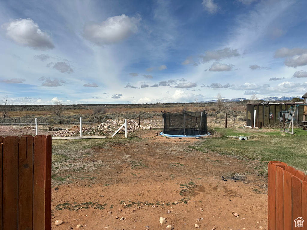 View of yard featuring fence, a trampoline, and a rural view
