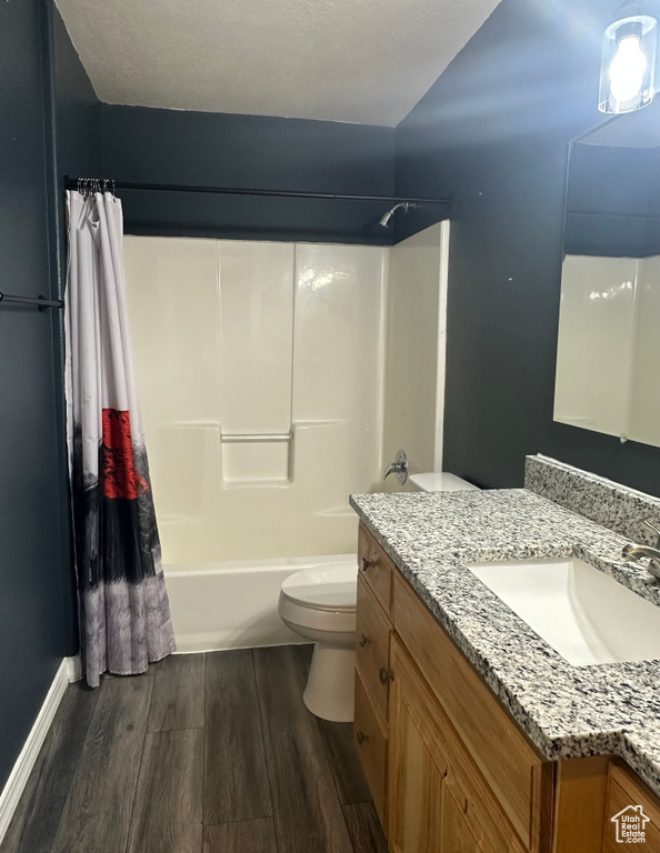Bathroom featuring toilet, wood finished floors, vanity, and shower / bath combo with shower curtain
