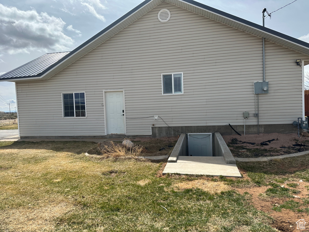 Back of property featuring a lawn and metal roof