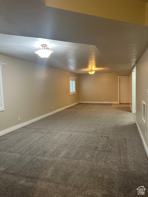 Below grade area with baseboards, visible vents, and carpet