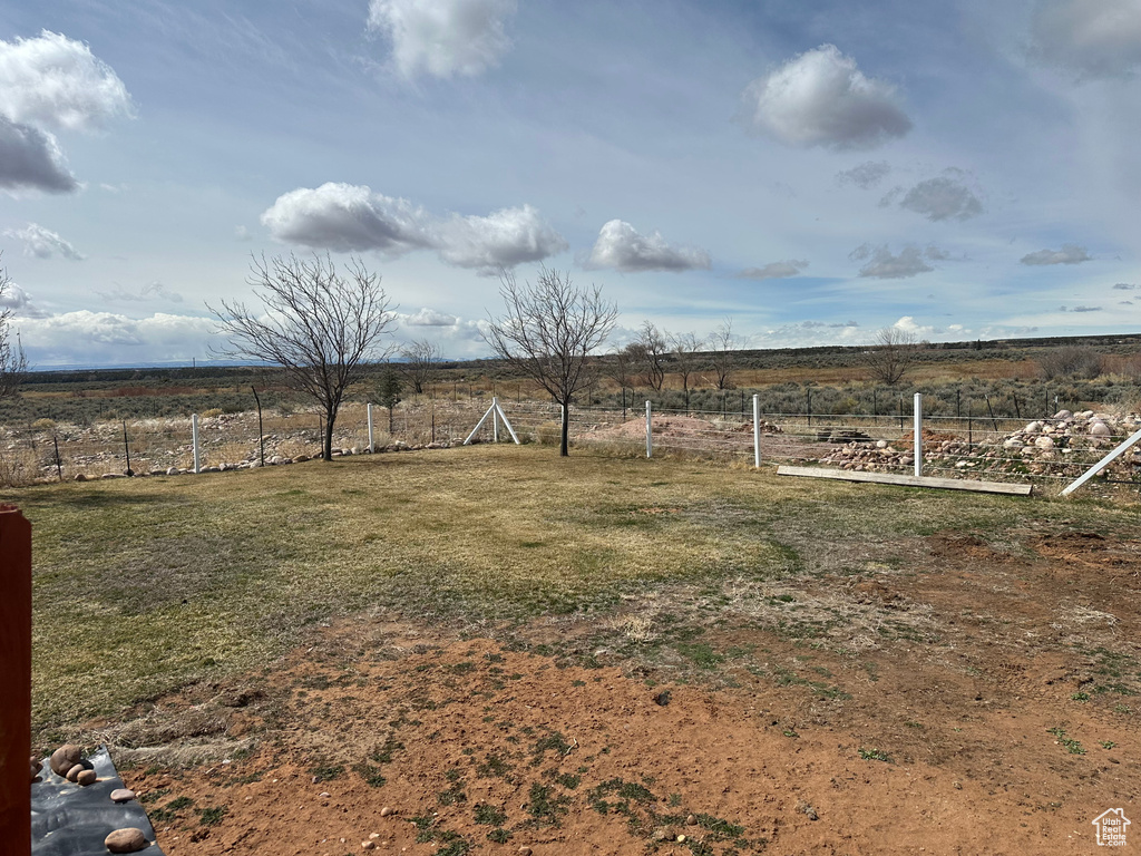 View of yard with fence and a rural view