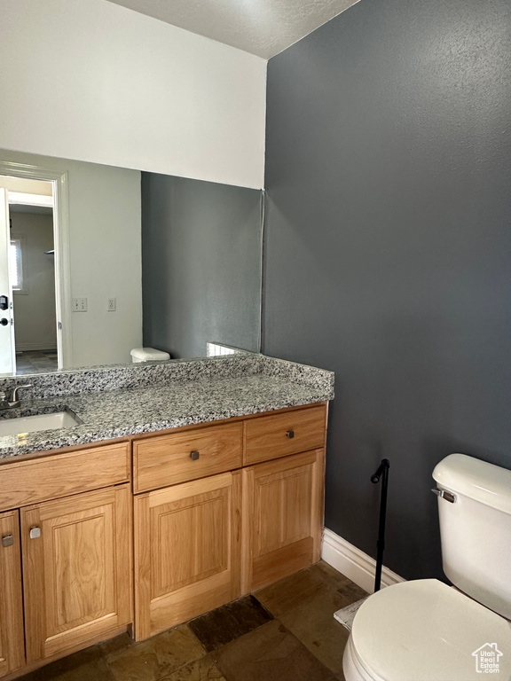 Half bathroom with toilet, vanity, and baseboards
