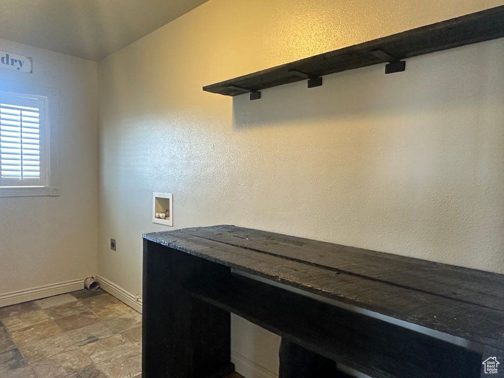 Laundry area with hookup for an electric dryer, baseboards, stone finish flooring, laundry area, and washer hookup