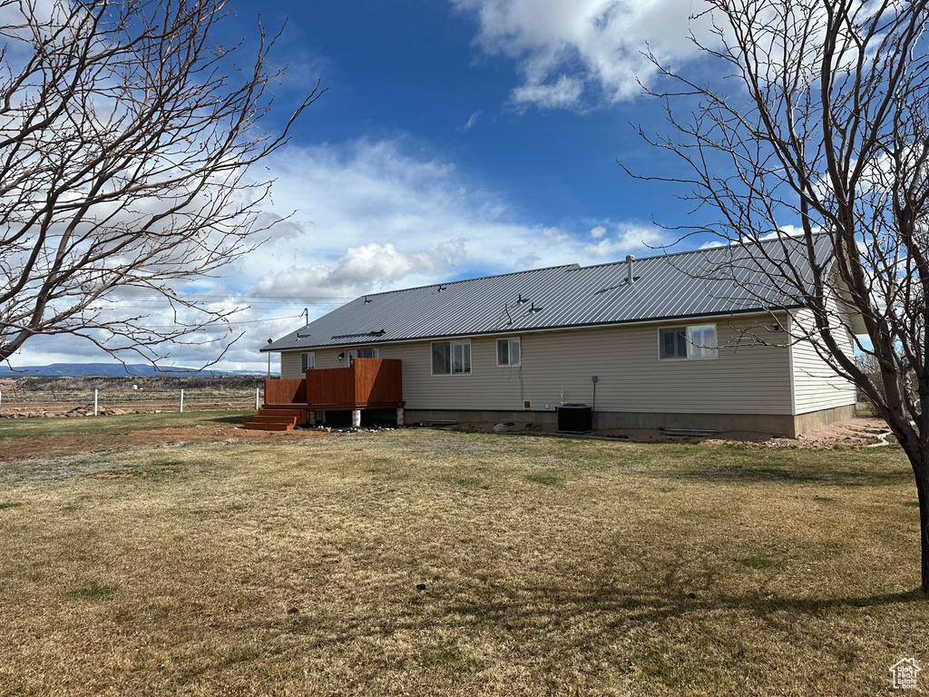 Rear view of house with a lawn, metal roof, central air condition unit, and a deck