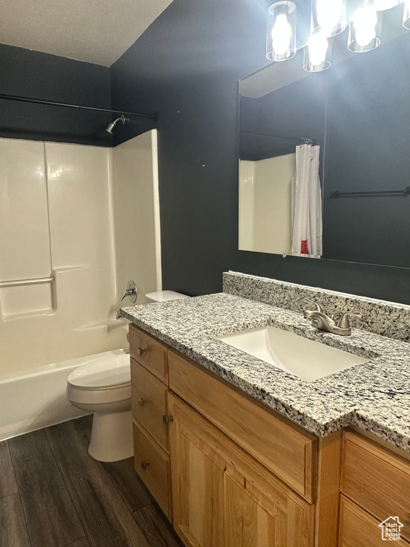 Full bathroom with toilet, vanity, shower / tub combo, and wood finished floors