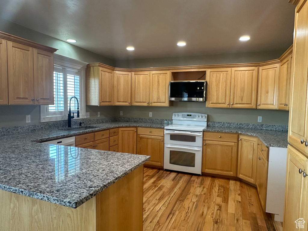 Kitchen featuring double oven range, stainless steel microwave, a sink, light wood-style floors, and a peninsula