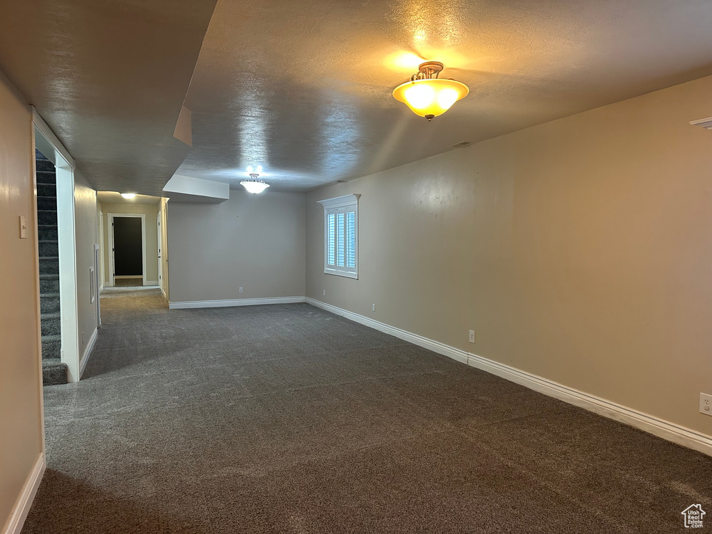 Interior space with baseboards, dark colored carpet, and a textured ceiling