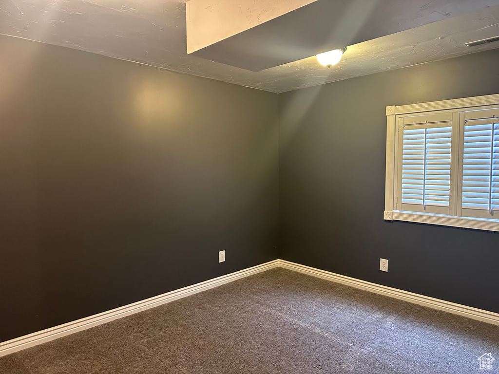 Carpeted spare room featuring baseboards and visible vents