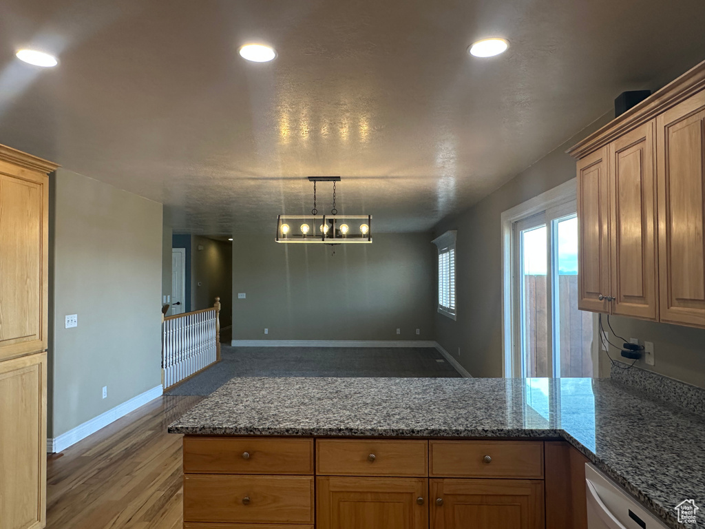 Kitchen with recessed lighting, dark stone counters, light wood finished floors, dishwasher, and a peninsula