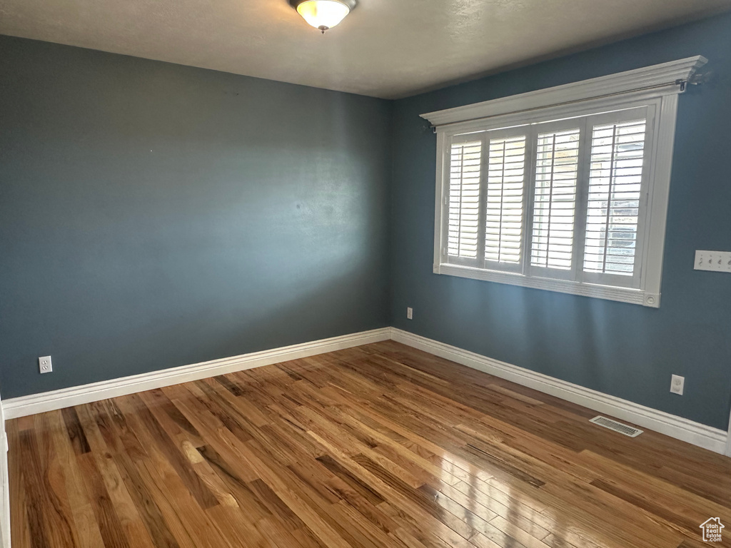 Empty room featuring baseboards, visible vents, and wood finished floors
