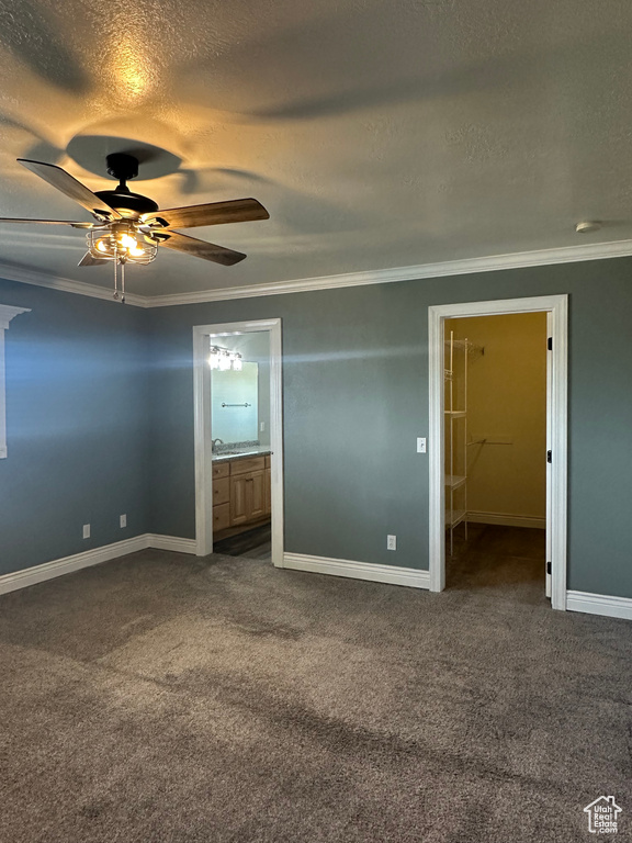 Unfurnished bedroom featuring baseboards, crown molding, dark colored carpet, and a textured ceiling