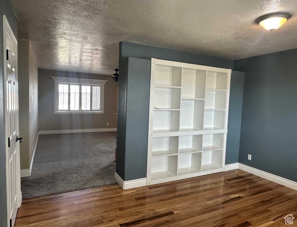 Interior space with baseboards, a textured ceiling, and wood finished floors