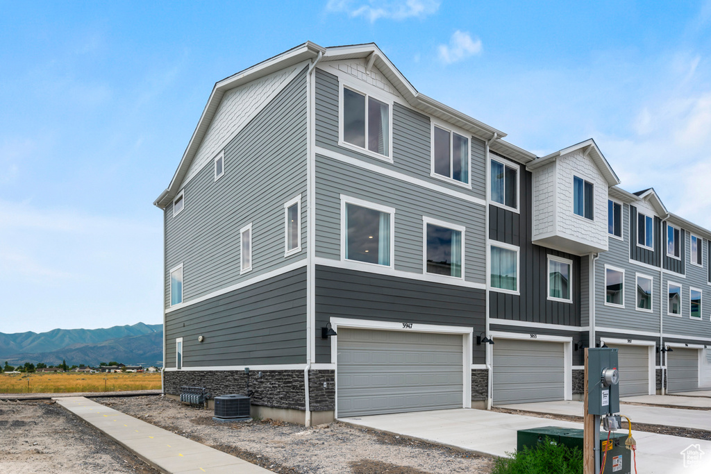 View of front facade featuring driveway, stone siding, an attached garage, board and batten siding, and a mountain view