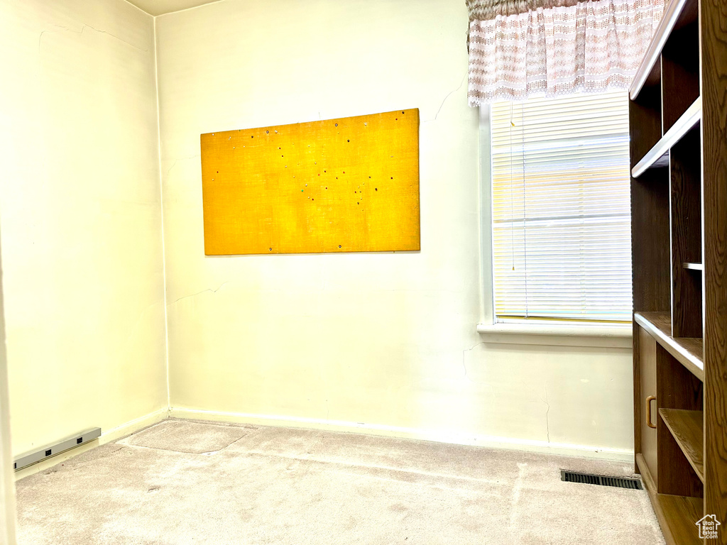 Carpeted spare room featuring baseboards