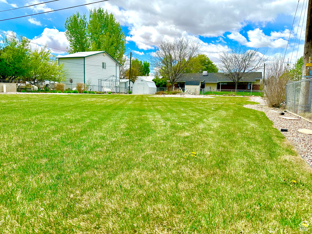 View of yard with fence, a storage unit, and an outdoor structure